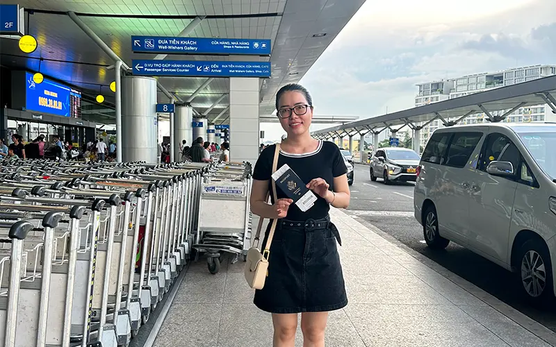 Chị An cầm trên tay hộ chiếu Hoa Kỳ tại sân bay Tân Sơn Nhất trong chuyến viếng thăm quê hương