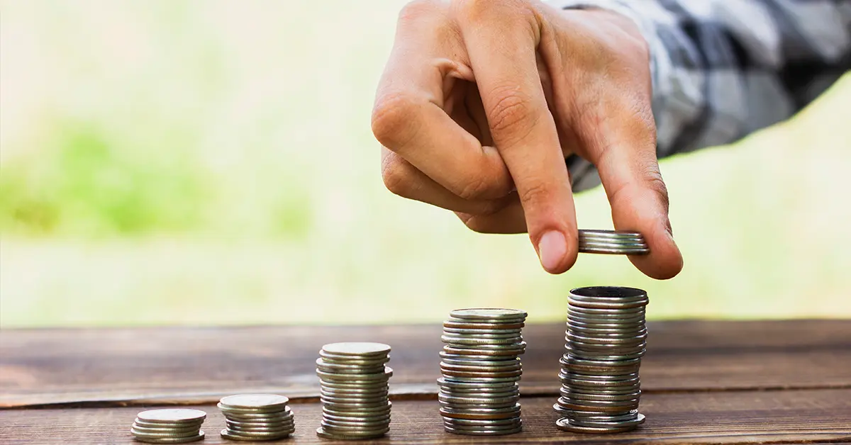 Người đàn ông cầm những đồng xu và xếp chồng lên nhau.