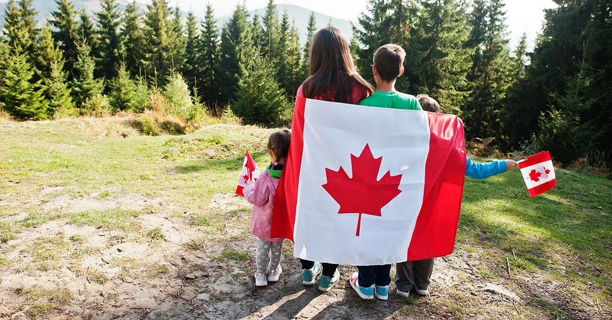 Gia đình hạnh phúc đang cầm lá cờ Canada trên tay và quấn vào người