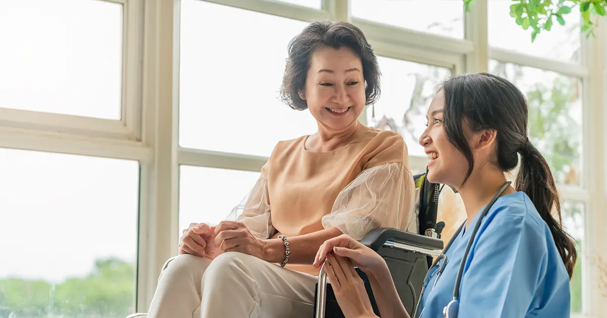 Người chăm sóc trẻ châu Á chăm sóc bệnh nhân lớn tuổi của mình tại nhà trẻ dành cho người cao tuổi Bệnh nhân khuyết tật ngồi xe lăn tại bệnh viện đang nói chuyện với một y tá thân thiện và trông y tá vui vẻ đang đẩy xe lăn Bệnh nhân cao tuổi