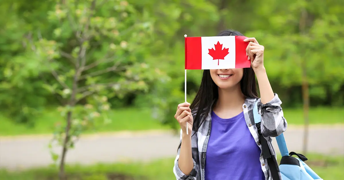 Sinh viên quốc tế đang cầm trên tay lá cờ Canada trong khuôn viên sân trường đại học