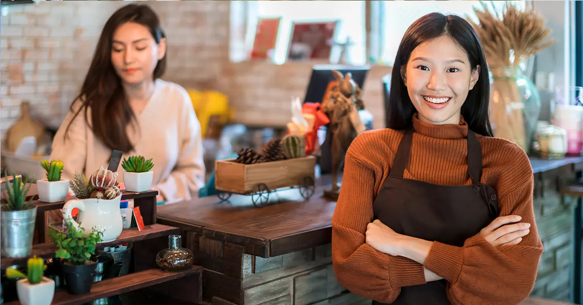 Chủ quán cà phê châu á xinh đẹp hấp dẫn mỉm cười hạnh phúc và vui vẻ với tạp dề tách cà phê nền quán cà phê