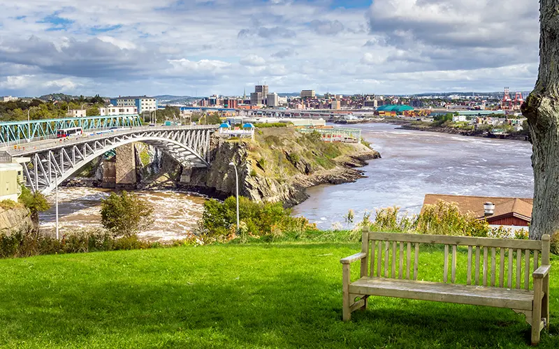 Saint John, New Brunswick, từ một công viên gần Cầu Reversing Falls. Một chiếc ghế gỗ trống ở phía trước.