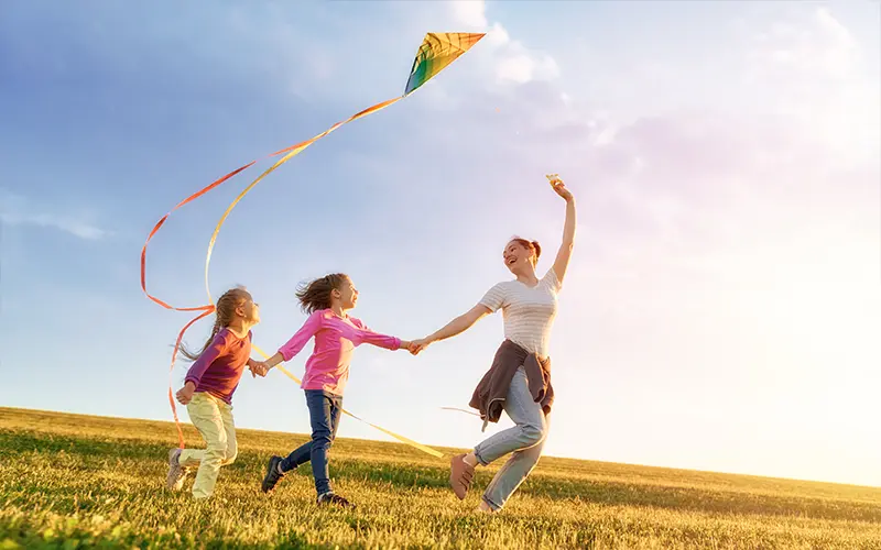 Gia đình hạnh phúc chơi ngoài trời. Mẹ và con chạy trên đồng cỏ với diều vào mùa hè giữa thiên nhiên.