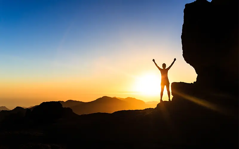 Hình bóng thành công của người phụ nữ leo núi trên núi, đại dương và hoàng hôn