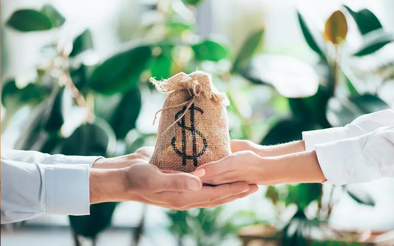 bức ảnh cắt xén của những người đang cầm túi vải thô với ký hiệu đô la trên tay