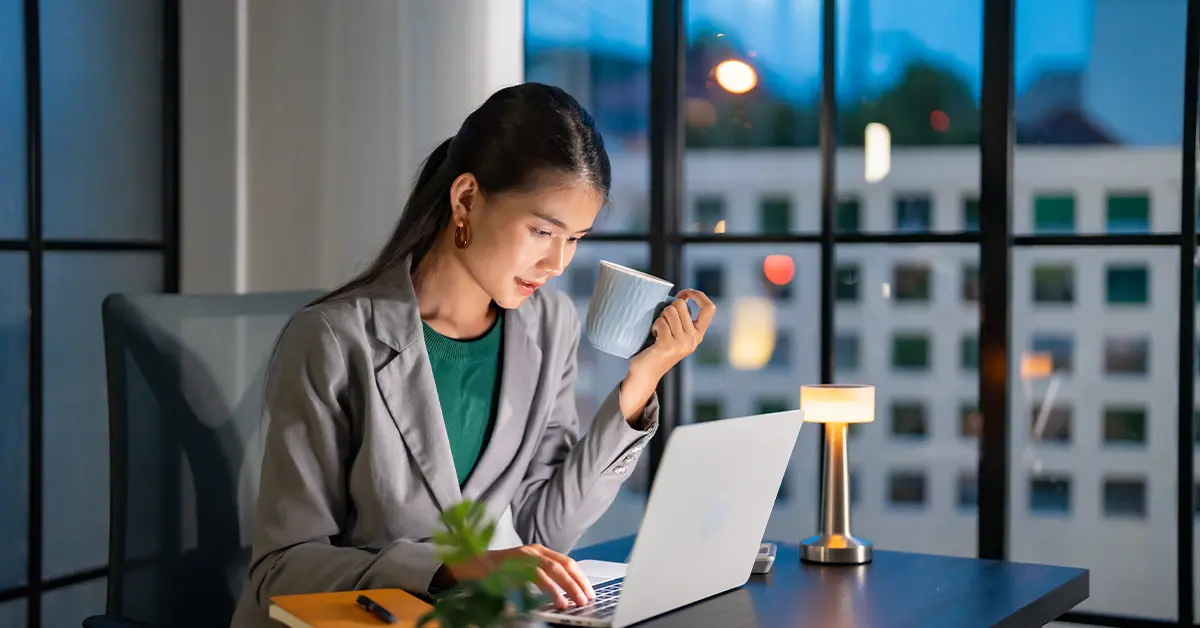Làm việc một mình vào đêm khuya. Nữ doanh nhân châu Á tại nơi làm việc trong văn phòng làm việc vào đêm khuya tại bàn làm việc trong một văn phòng tối làm việc trên máy tính xách tay vào buổi tối muộn