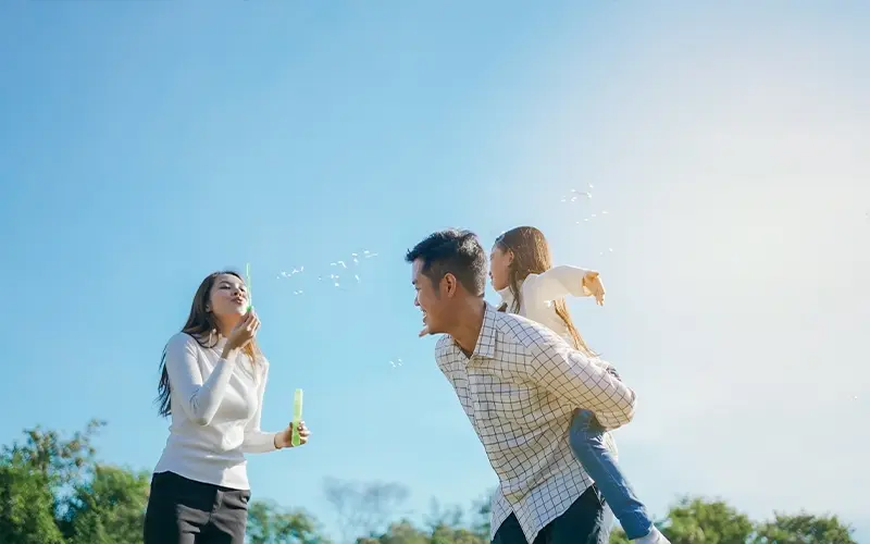 Gia đình châu Á hạnh phúc trong vườn Họ đang vui vẻ chơi đùa và thổi bong bóng và tận hưởng cùng nhau trong khu vườn xanh. Gia đình tận hưởng ngày thu đầy nắng giữa thiên nhiên.