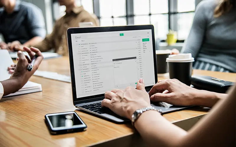 Người phụ nữ đang kiểm tra email của mình trong một cuộc họp