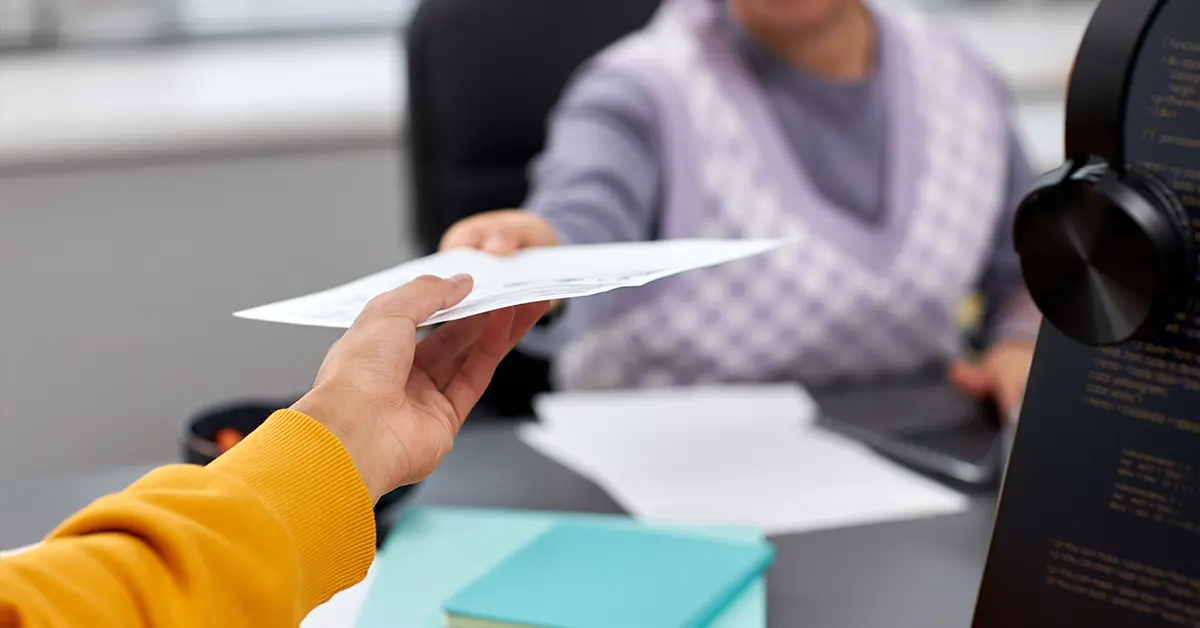 Cận cảnh hai thanh niên đang trao tài liệu qua bàn