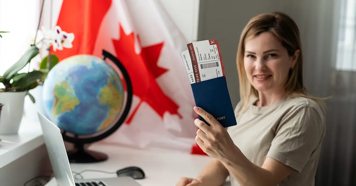 Người sinh viên nữ đang ngồi cầm cờ Canada và sử dụng máy tính xách tay