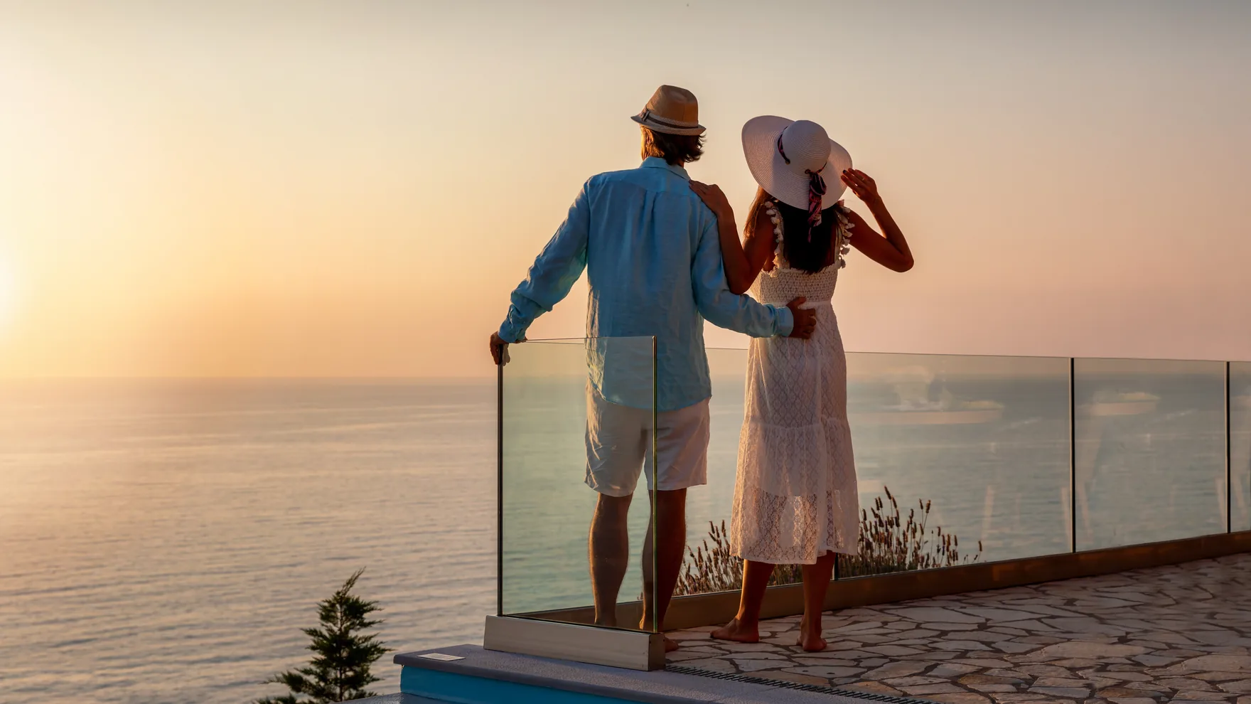 A couple by an infinity pool overlooking the Mediterranean — citizenship, residency and international real estate services from Prosperous Living Investment