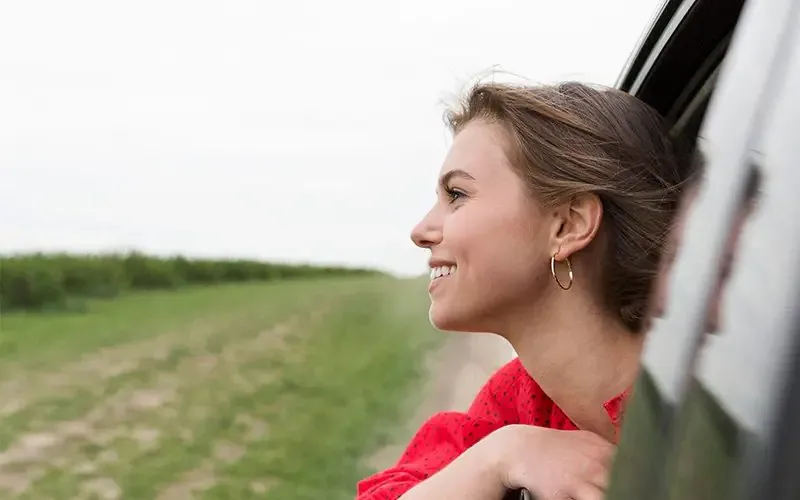 Người phụ nữ nhìn ra cửa sổ xe trên đường đi